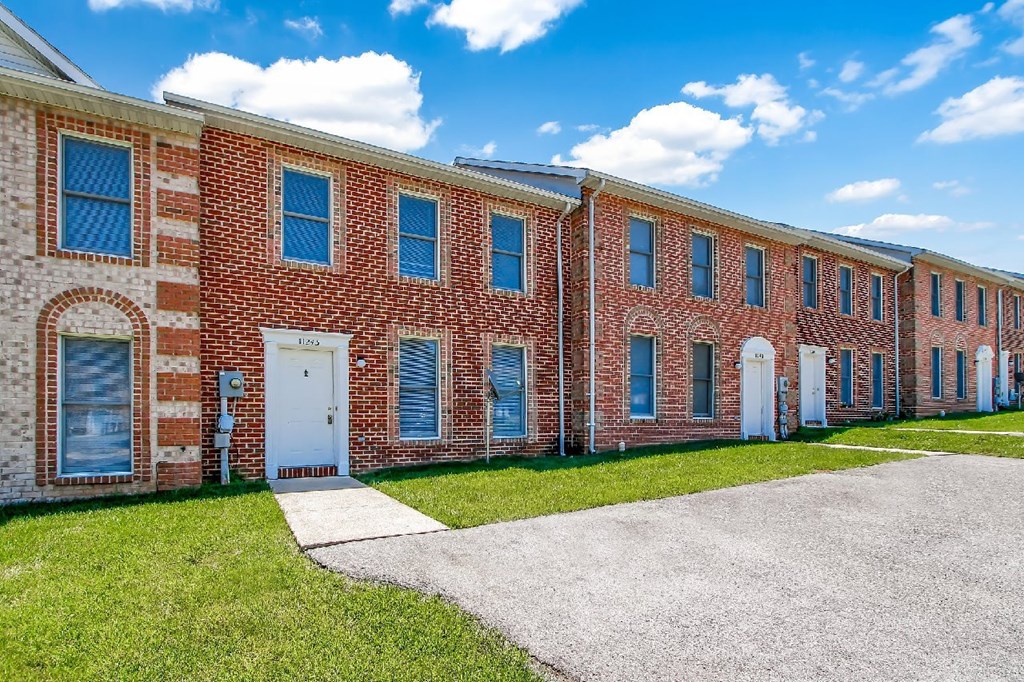 A long brick building with a white door and windows.