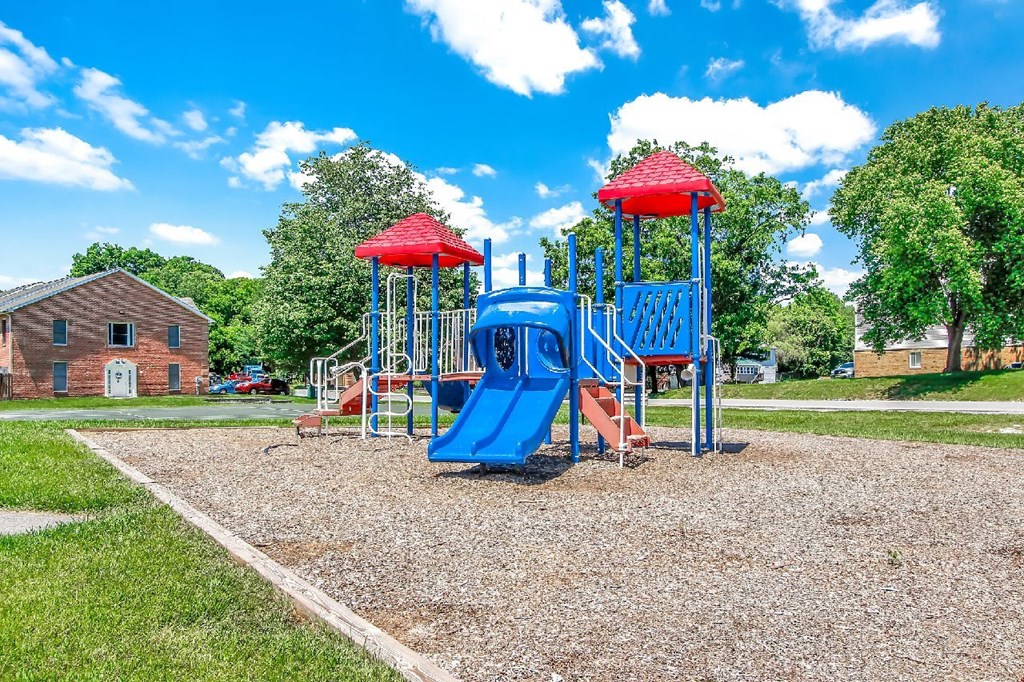 A playground with a blue slide and red roofed structure.