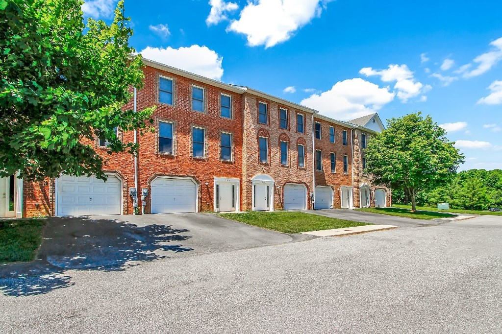 A large red brick building with a parking lot in front.