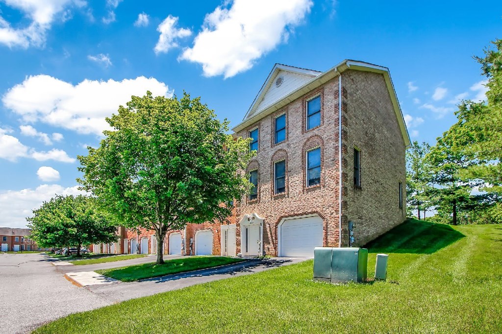 A large brick building with a green lawn in front.