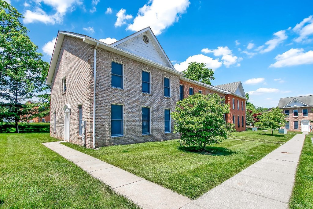 A brick building with a white roof and a walkway in front.