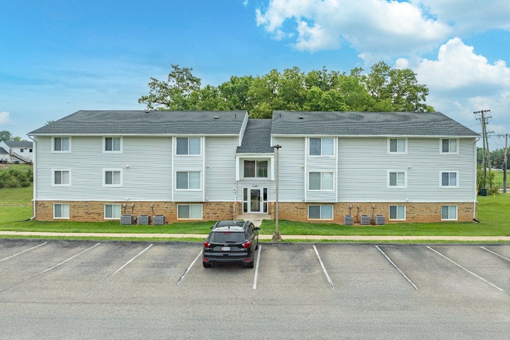 A car is parked in a parking lot in front of a building.