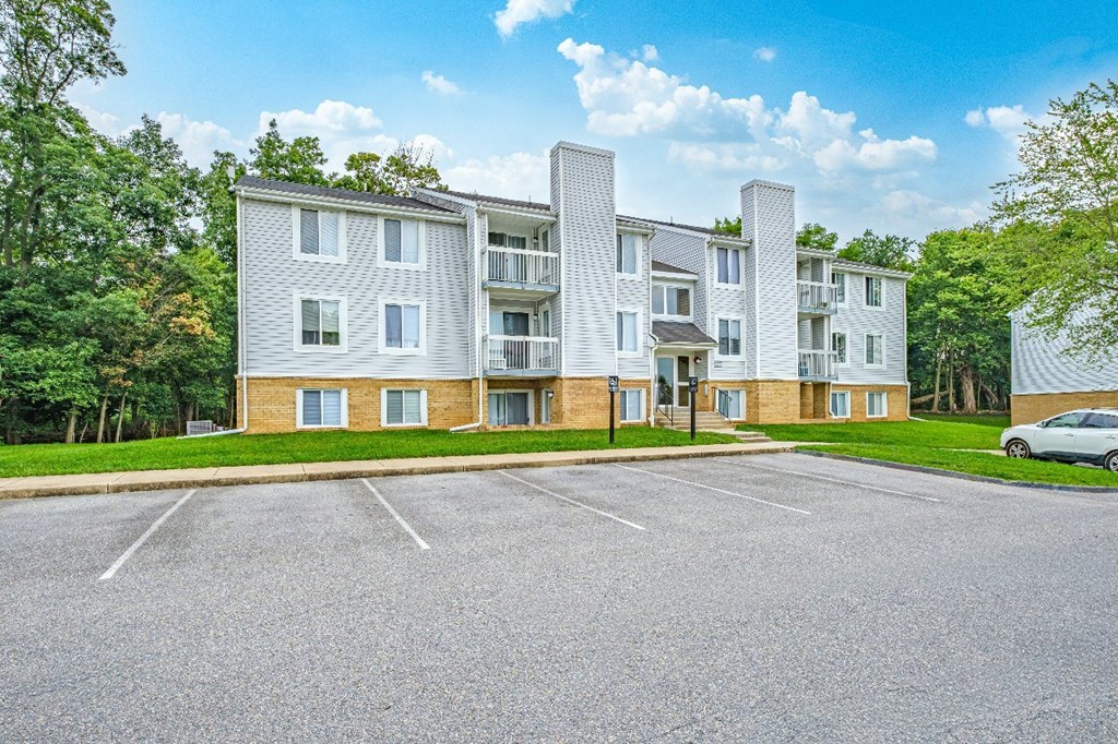 A large apartment complex with a parking lot in front.