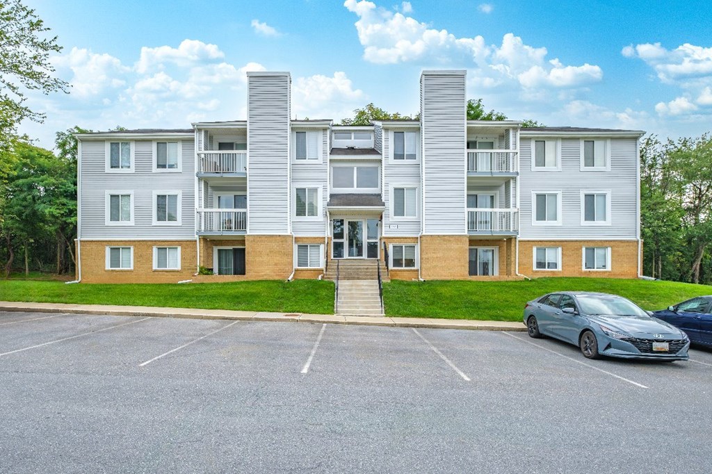 A large apartment complex with a parking lot in front.