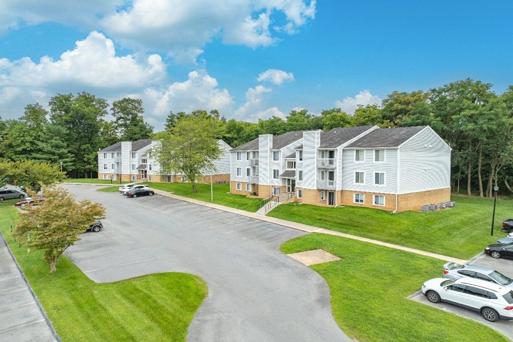 A sunny day at a residential complex with cars parked in the driveway.