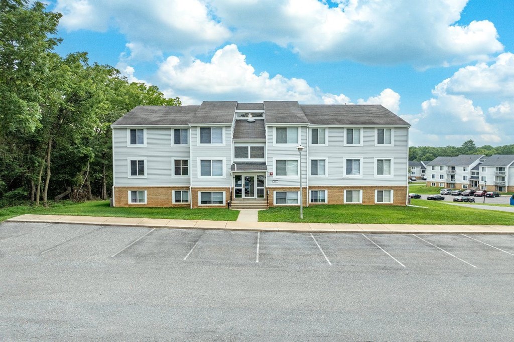 A large white building with a parking lot in front.