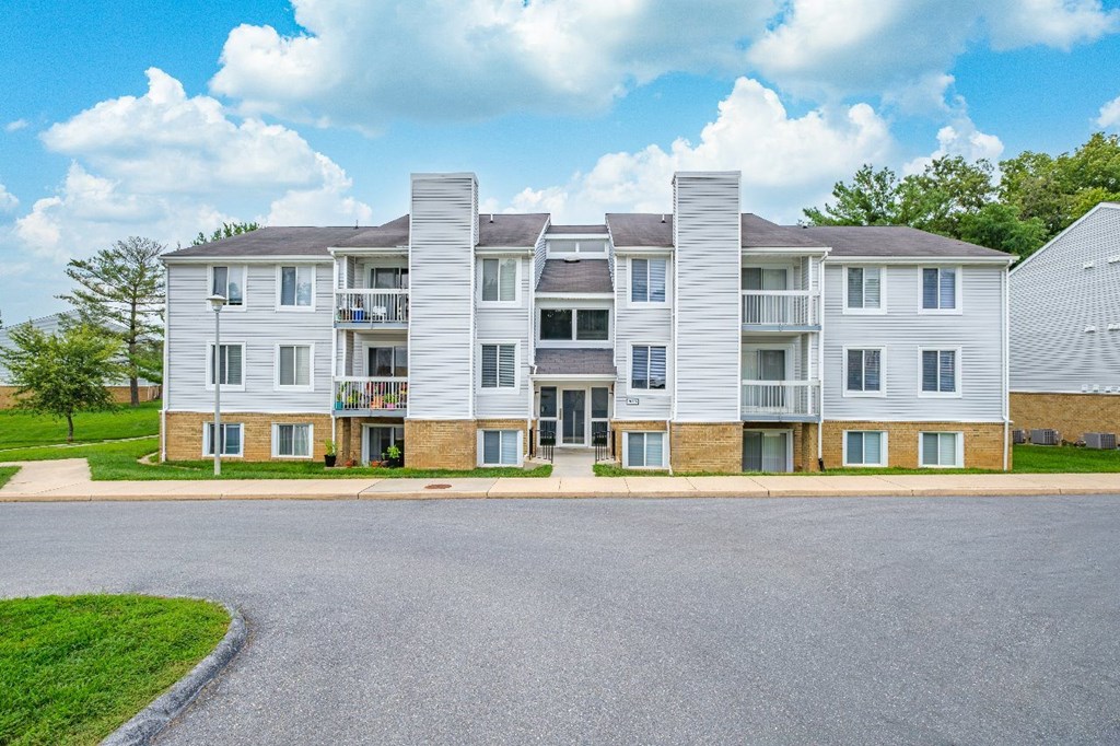 A large apartment complex with a parking lot in front.