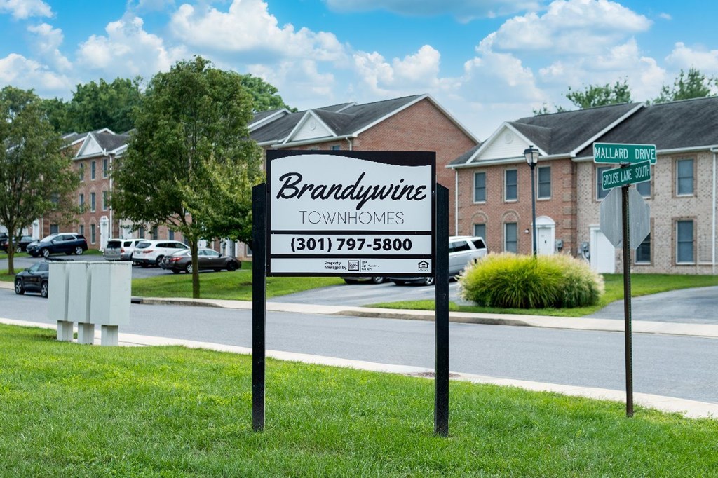 A sign for Brandywine Townhomes stands in front of a row of houses.