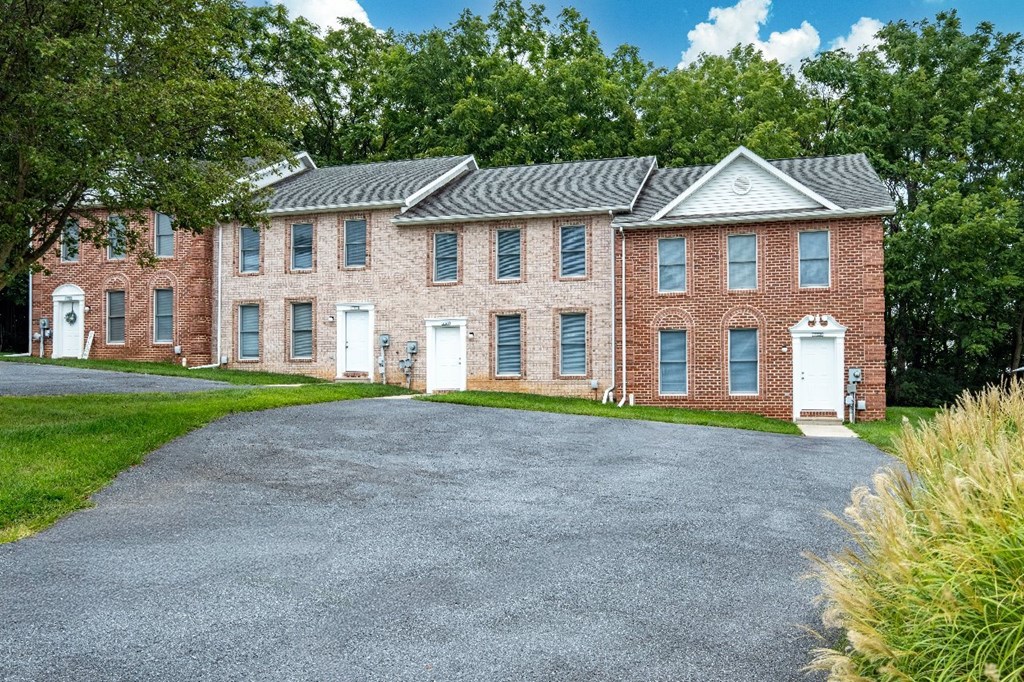 A large red brick house with a driveway in front.