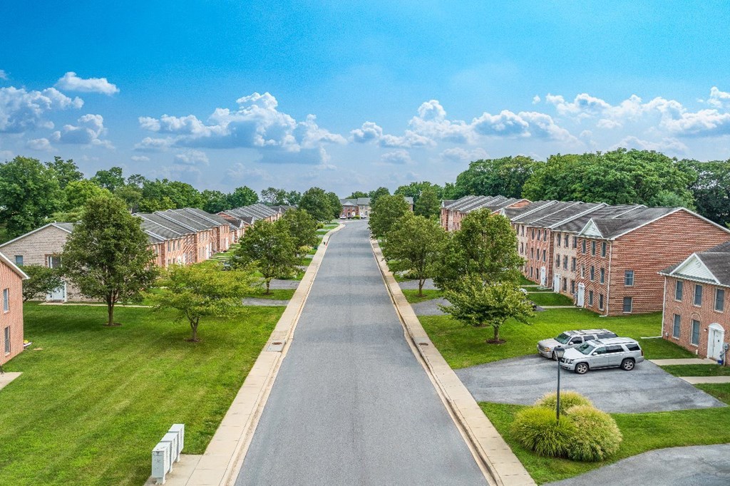 A street view of a residential area with houses on both sides and a car parked on the right.