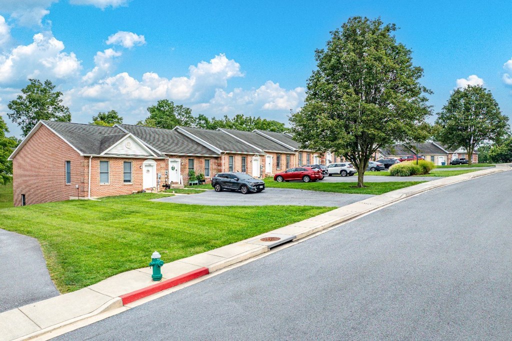 A street view of a residential area with houses and cars.