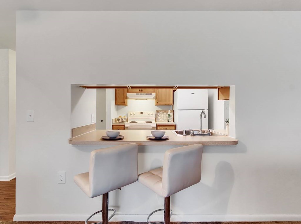 A kitchen with a white chair and a white fridge.