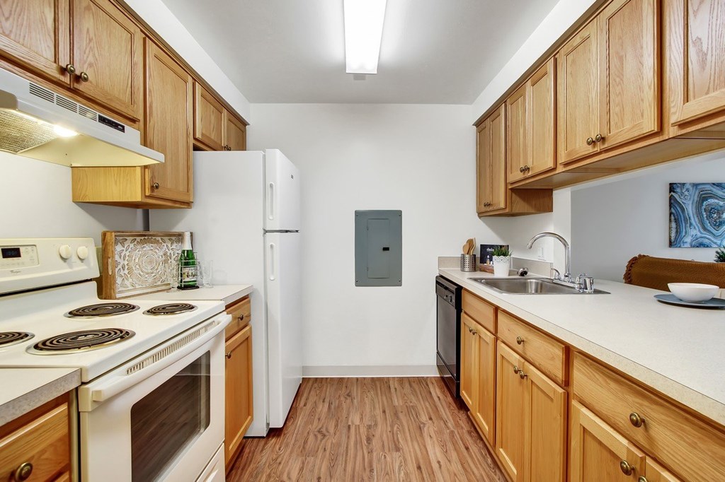 A kitchen with wooden cabinets and a white stove top oven.