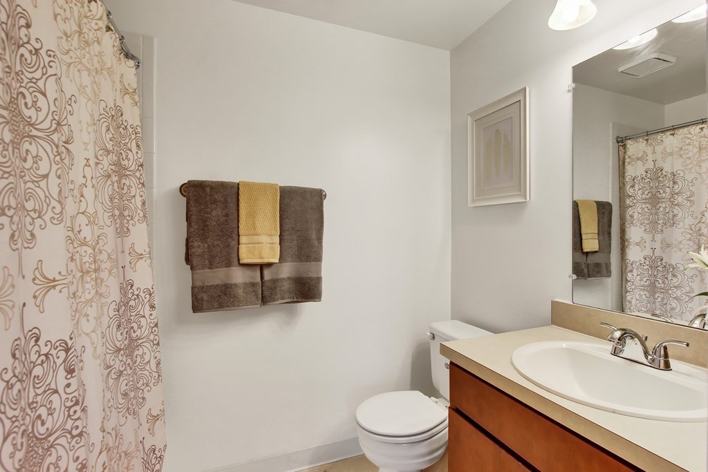 A bathroom with a toilet, sink, and a towel hanging on the wall.