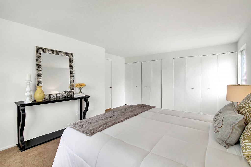 A bedroom with a large bed and a mirror on the wall.