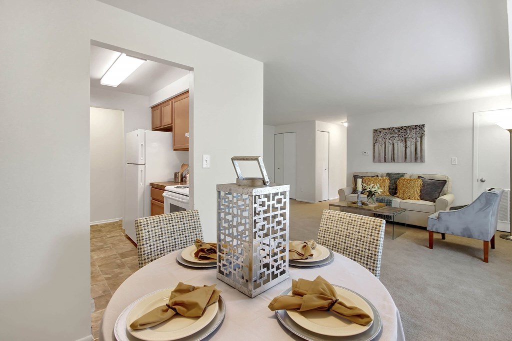 A dining table set with plates and napkins is in the middle of a room with a couch and chairs.