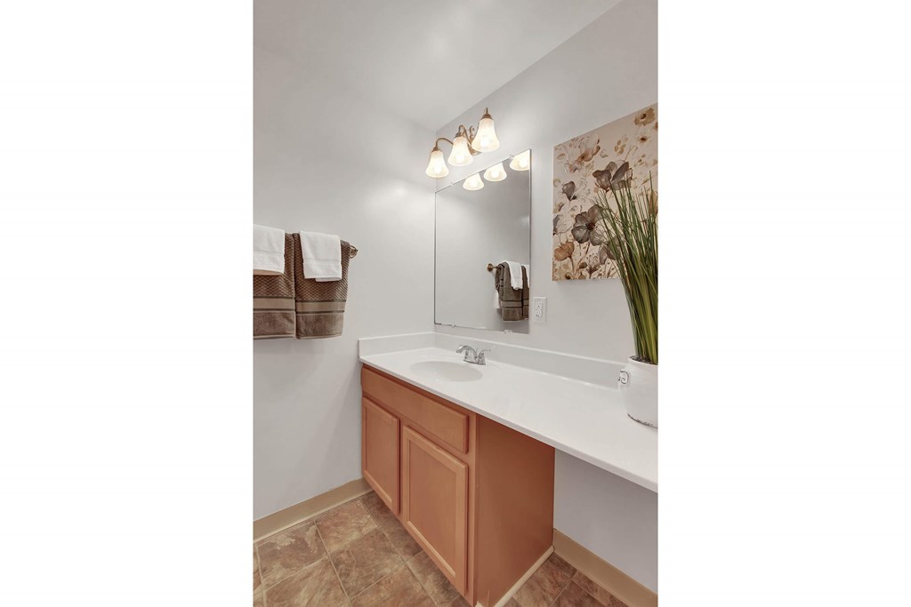 A bathroom with a white counter and brown cabinet.