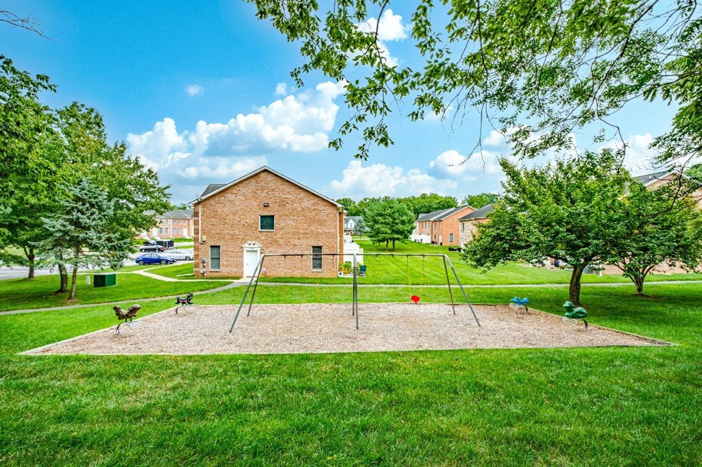 A playground with swings and a slide in front of a brick building.