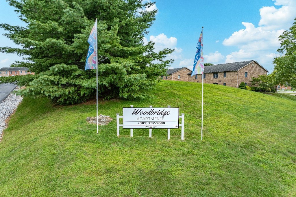 A sign that says Woodbridge stands in a grassy field.