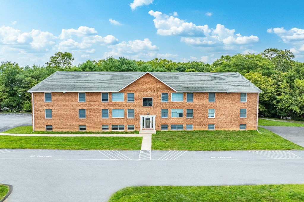 A large red brick building with a green lawn in front.