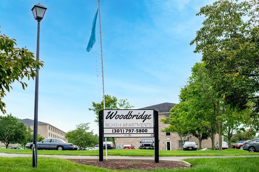 A sign for Woodbridge North Apartments stands in front of a building.