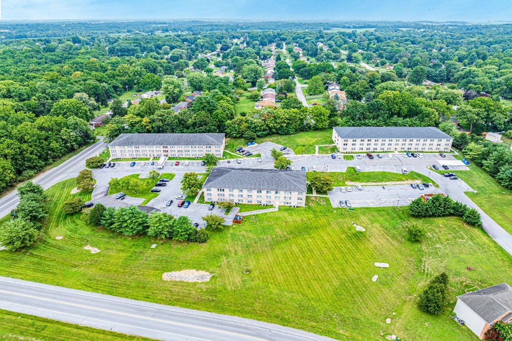 An aerial view of a large building surrounded by a green lawn and trees.