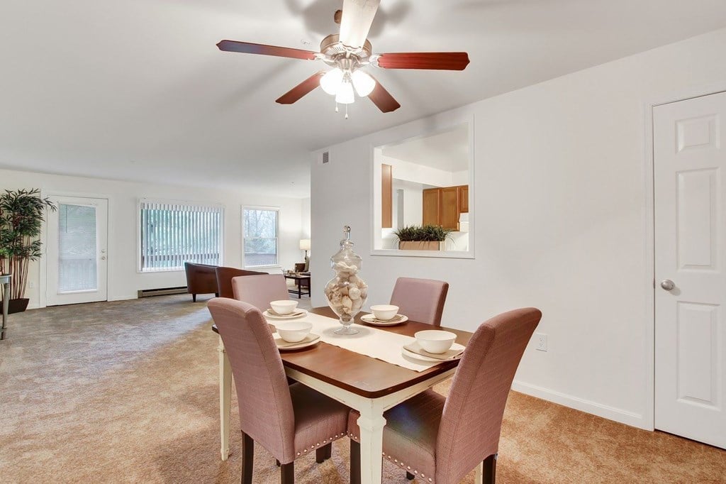 A dining room with a table set for two and a ceiling fan.