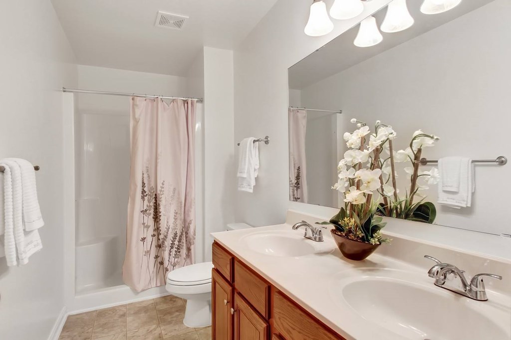 A bathroom with a pink shower curtain and a white toilet.