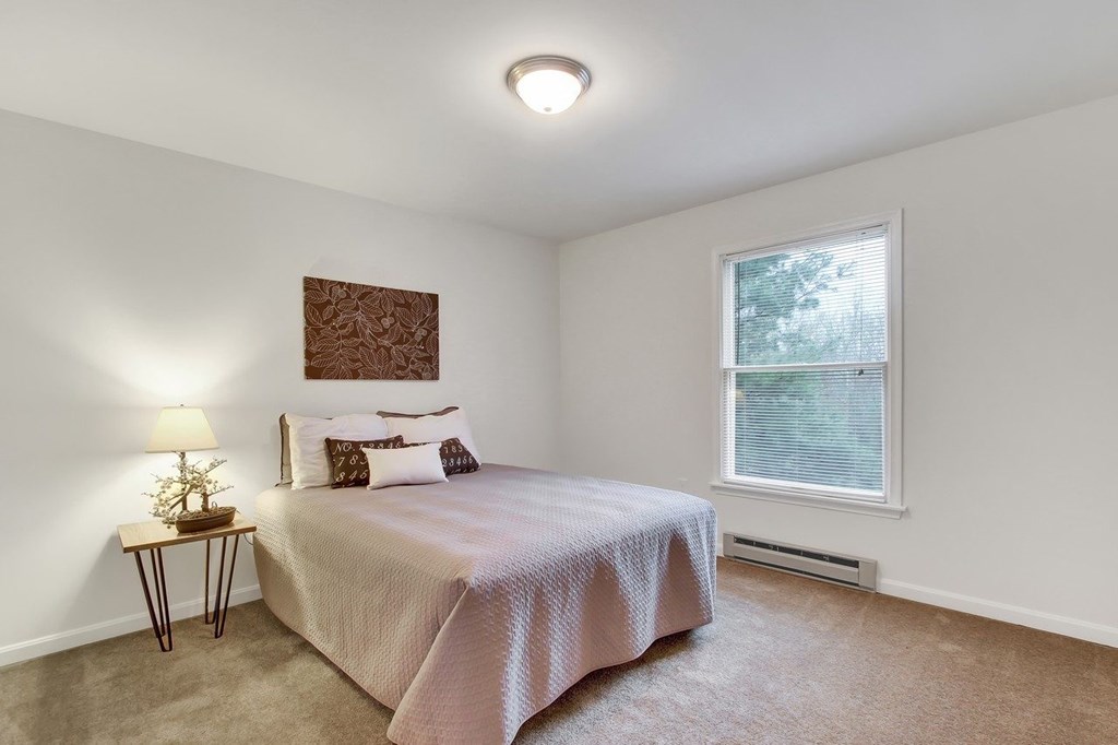 A bedroom with a bed, nightstand, and window.