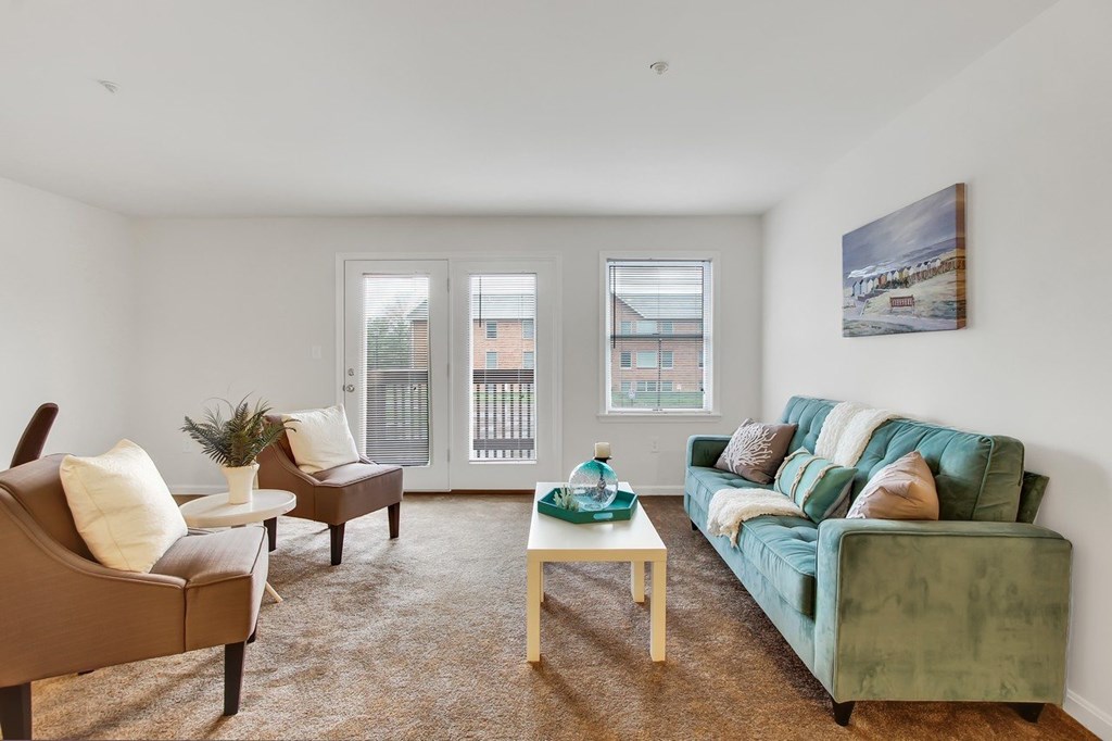 A living room with a green couch and brown armchairs.