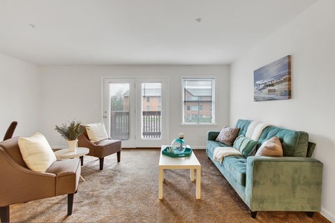 A living room with a green couch and brown armchairs.
