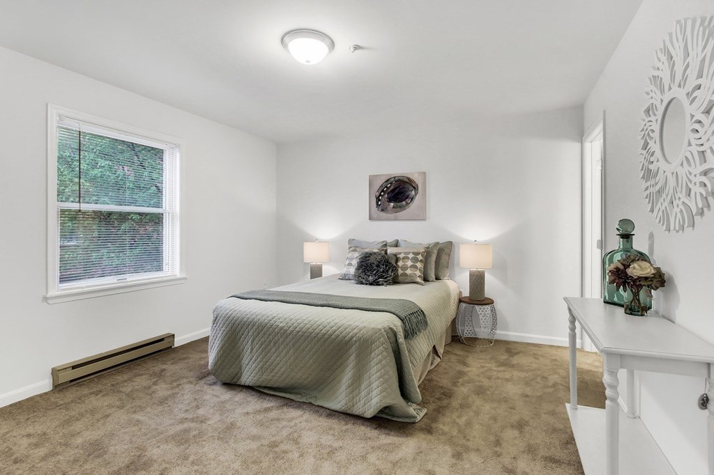A bedroom with a bed, nightstand, and window.