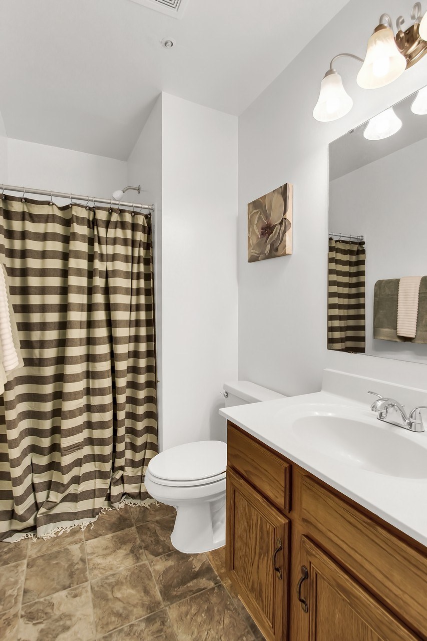 A bathroom with a white toilet and a brown shower curtain.