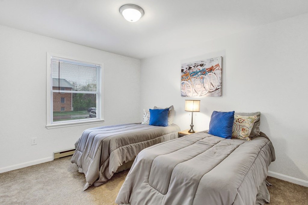 Two twin beds in a room with a painting on the wall.