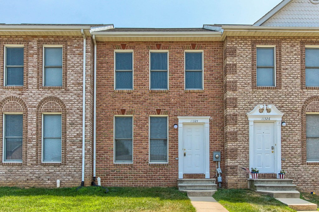 A brick house with a white door and windows.