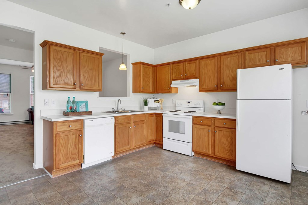 A kitchen with white appliances and wooden cabinets.