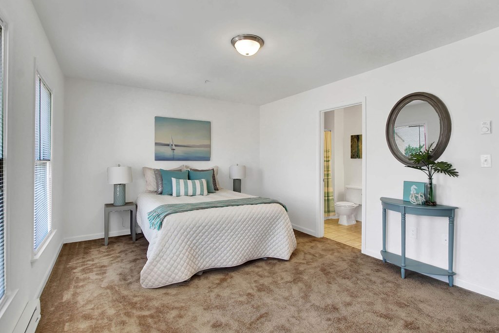 A bedroom with a bed, a mirror, and a painting on the wall.