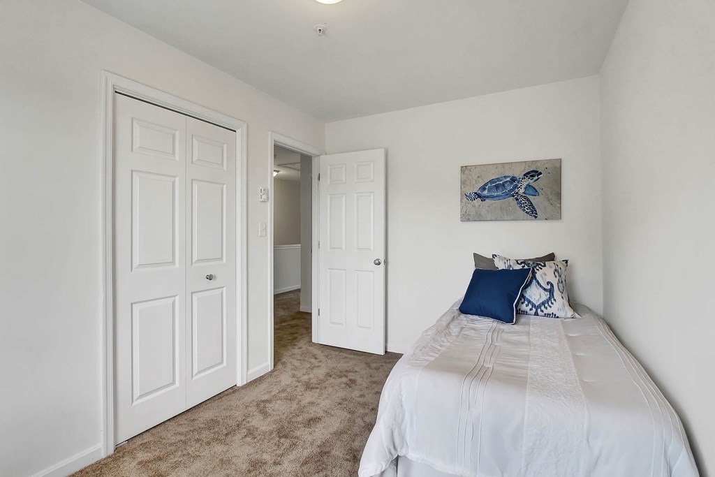 A bedroom with a bed, pillows, and a painting of a turtle on the wall.