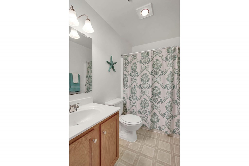 A bathroom with a white sink, toilet, and shower curtain.
