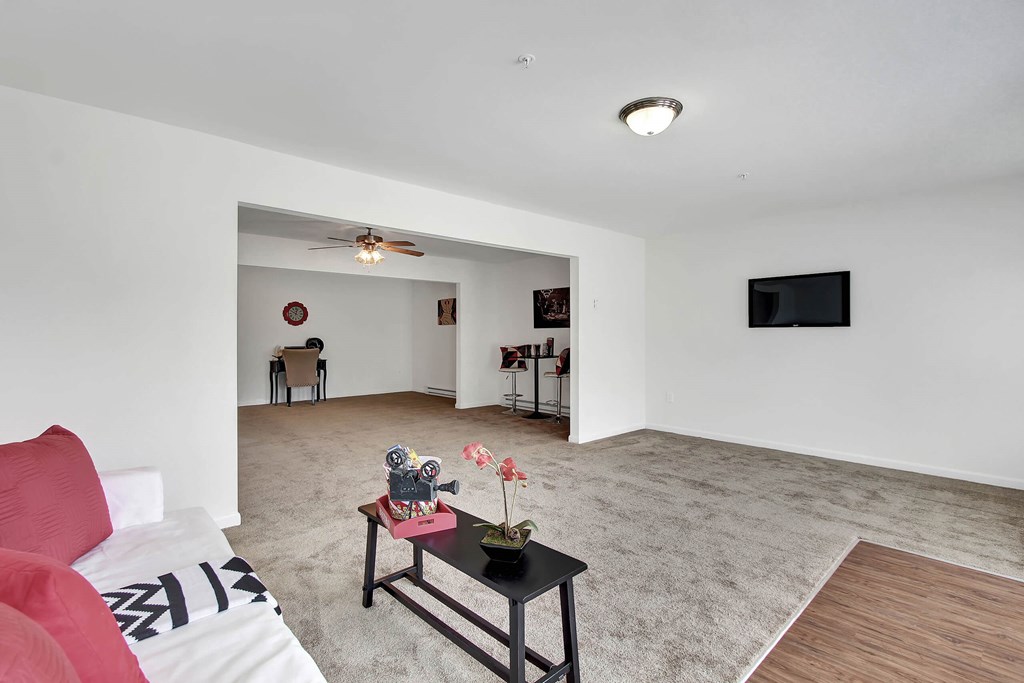A living room with a red couch and a television on the wall.