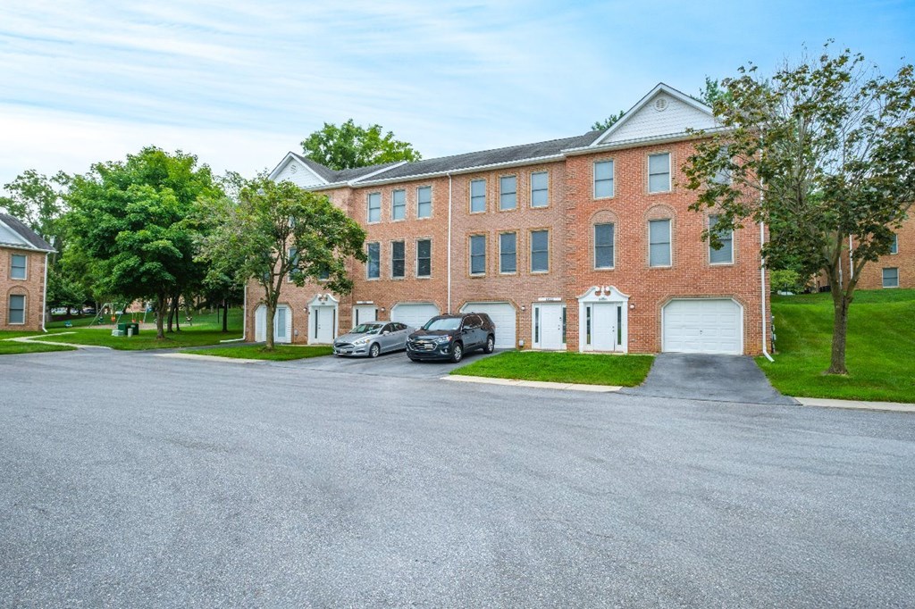 A large red brick building with a parking lot in front.