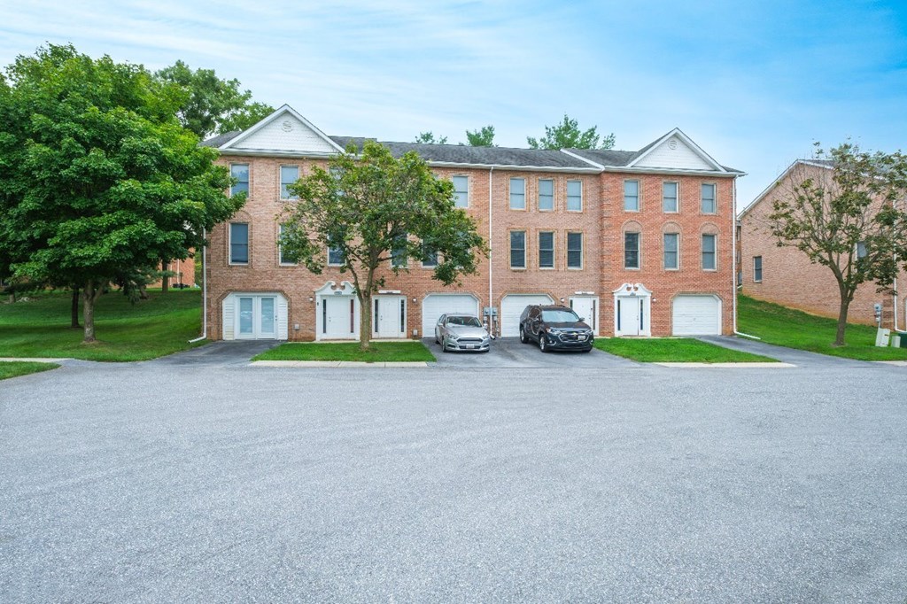 A large red brick building with a parking lot in front.