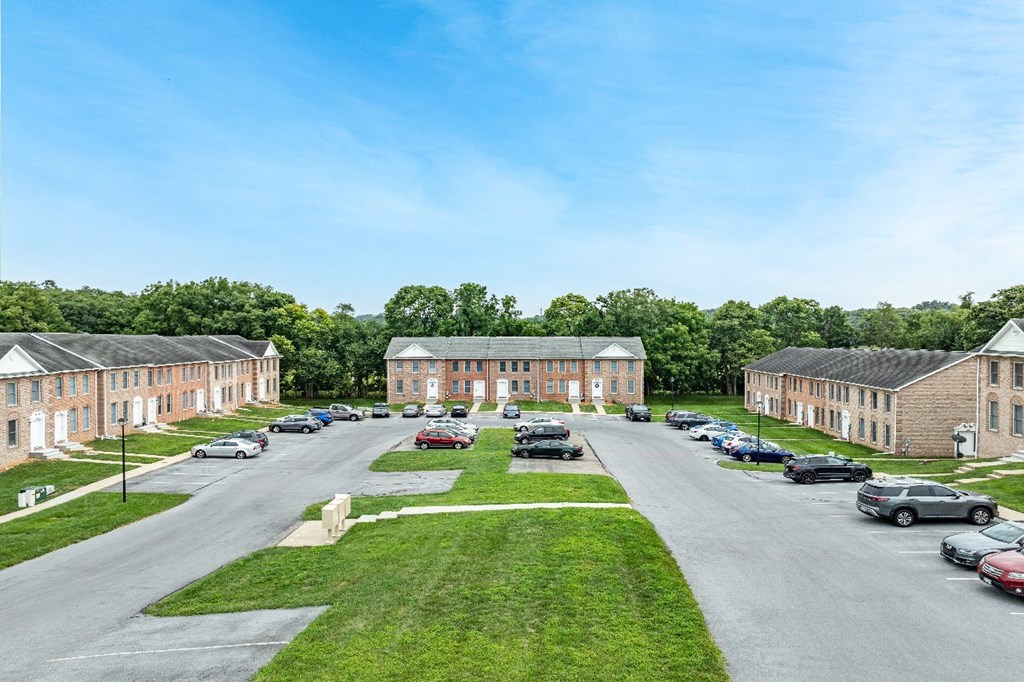 A parking lot in front of a building with a green lawn.