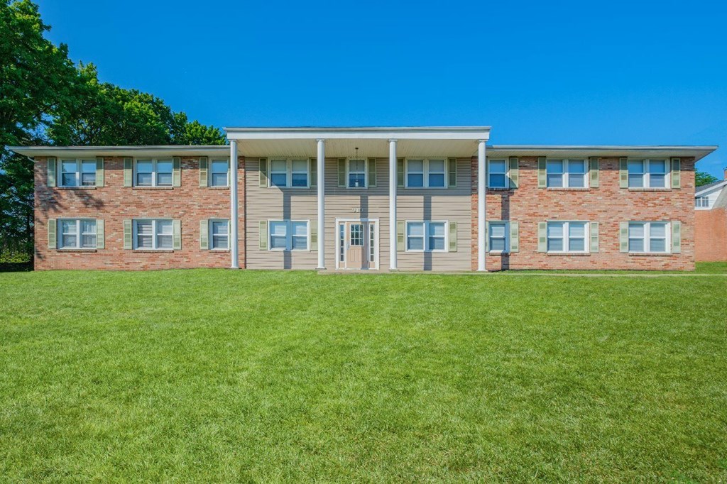 A large building with a green lawn in front.