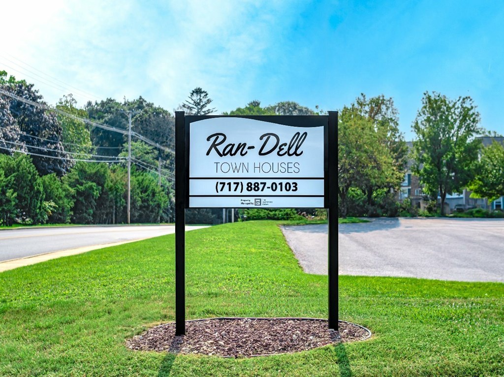 A sign for Ran-Dell Town Houses with a phone number on it.