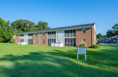 A building with a sign in front that says "Please keep grass.".
