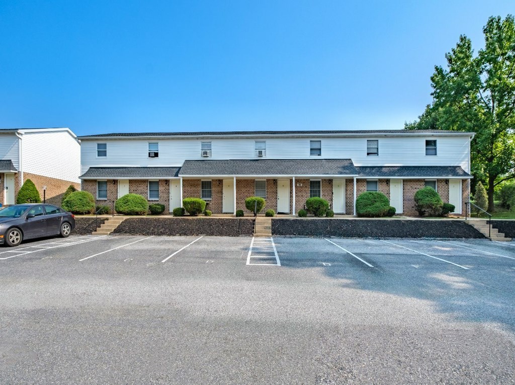 A parking lot in front of a building with a car parked on the left side.