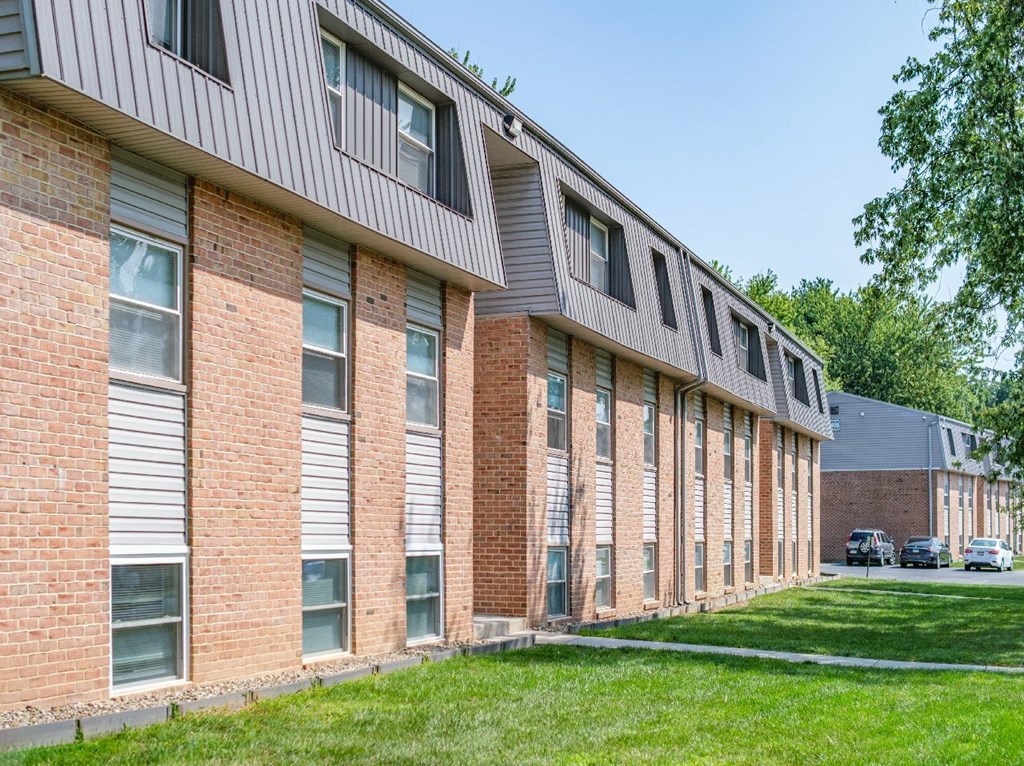 A long building with a lot of windows and a green lawn in front.