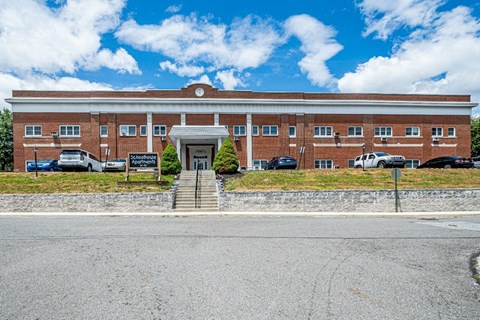 A red brick building with a white roof and a sign that says "Schoolhouse".