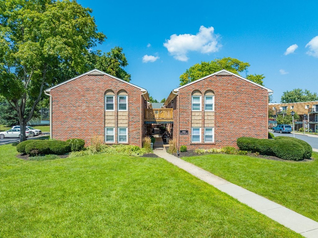 Two red brick buildings with green lawn in front.